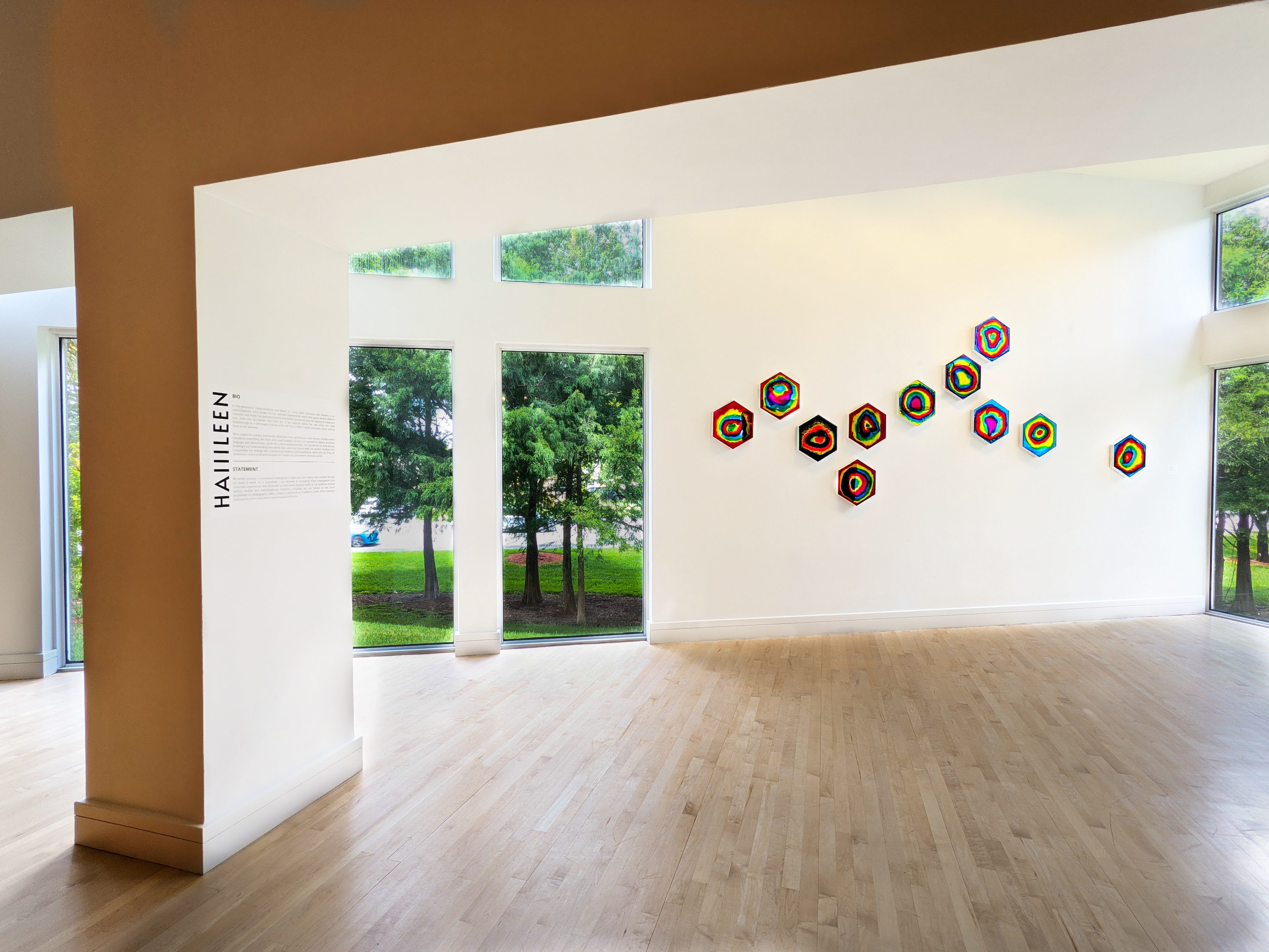 Visitors viewing Haiiileen’s hexagonal chromatic mirrors in the COLOR LIGHT SPACE exhibition at the Coral Springs Museum of Art.