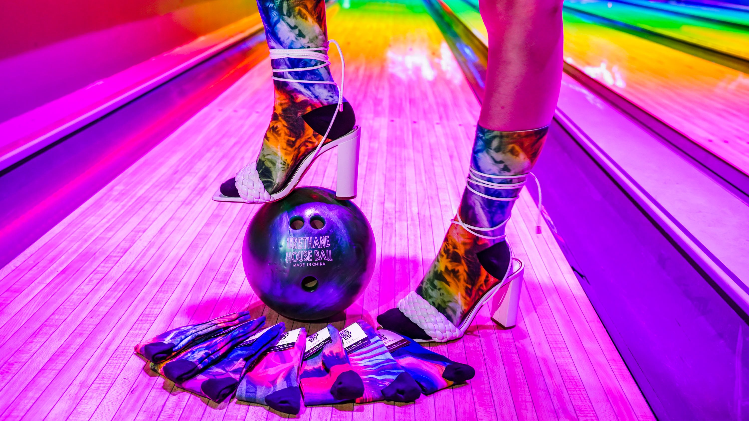 Colorful “Get Haiii Every Day” socks displayed under neon rainbow lighting from the Haiiileen x Tribe Socks collection.