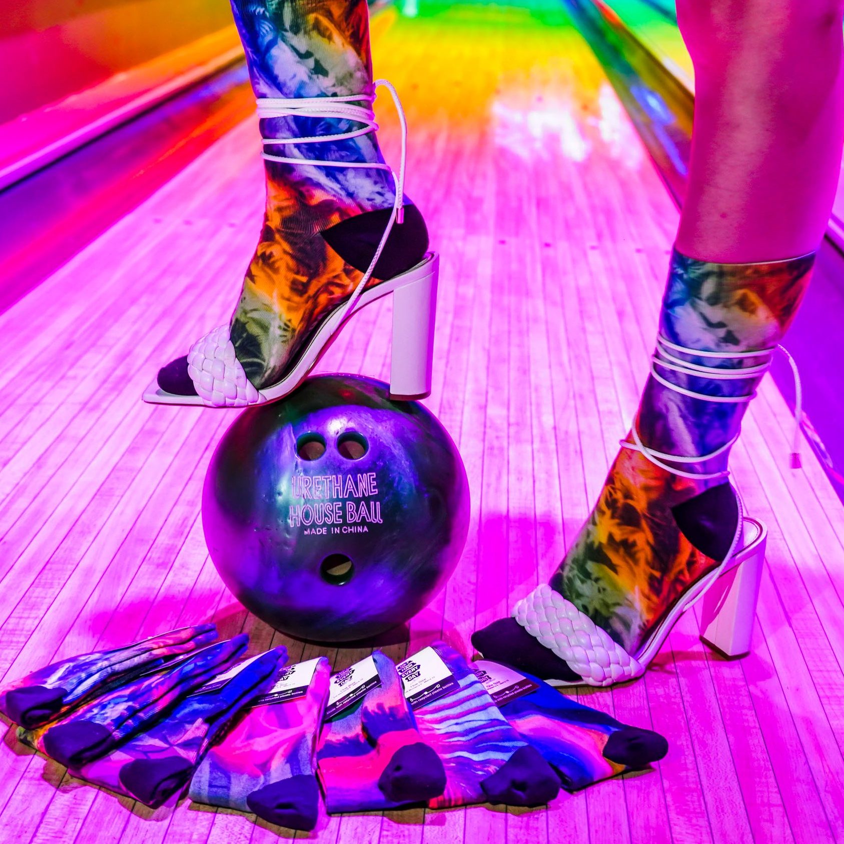 Colorful “Get Haiii Every Day” socks displayed under neon rainbow lighting from the Haiiileen x Tribe Socks collection.